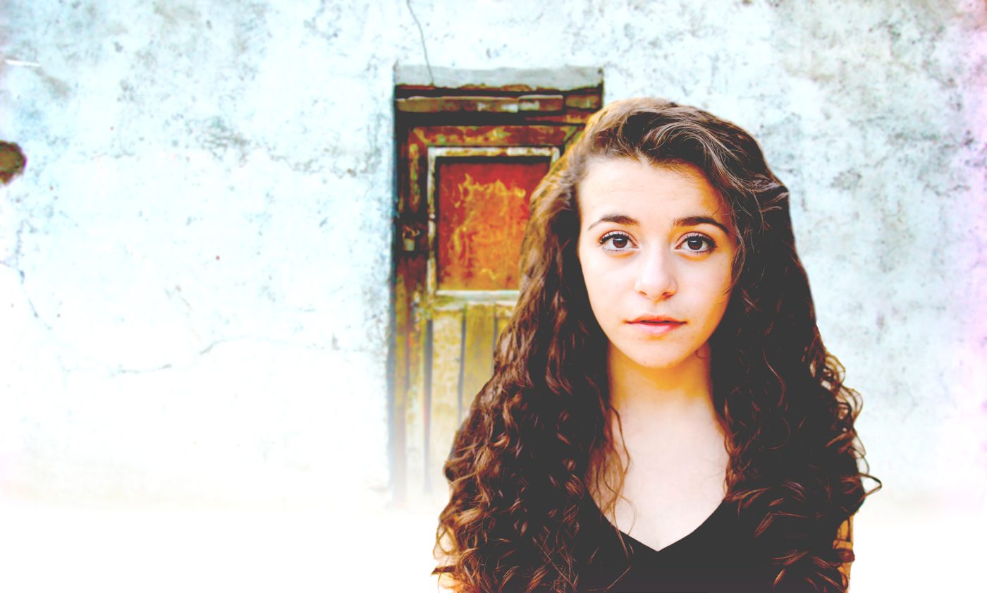 A teenage girl standing in front of an old weathered door
